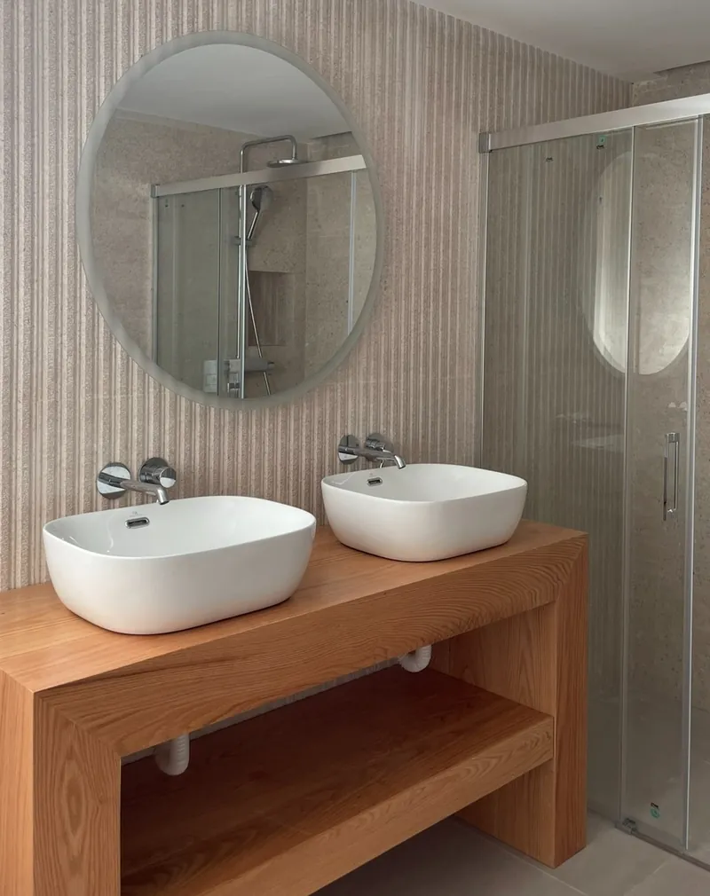 Baño infantil con mueble a medida de madera maciza, dos lavabos y espejo redondo