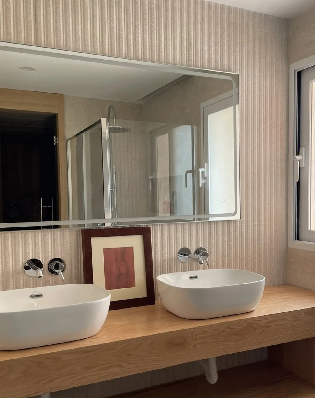 Baño con doble lavabo sobre mueble de madera