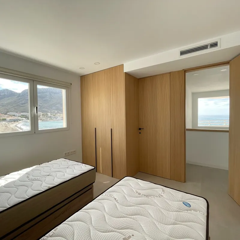 Dormitorio con armarios de madera y ventana con vistas al mar